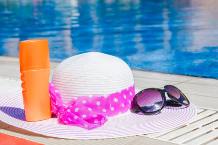 beautiful hat near the pool with cream and glasses background