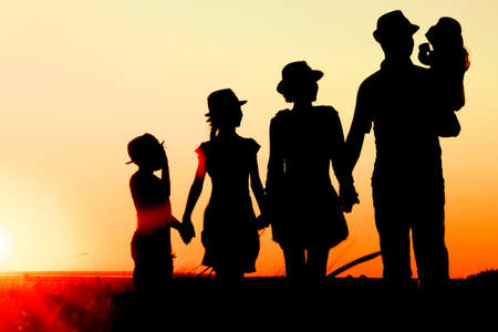 Happy family by the sea at sunset in travel silhouette in nature