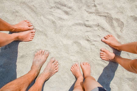 Feet on the sand of happy people by the sea on nature travel