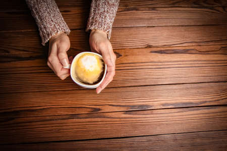 female hands and coffee on wooden backgroundの写真素材