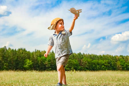 Baby boy by the plane plays on nature in the park. Boy on vacation pilot.の写真素材