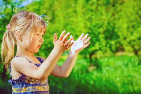 happy child blowing bubbles on nature in pairsの写真素材