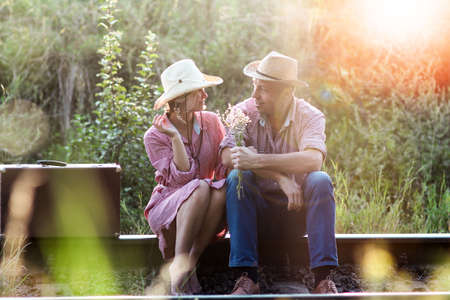 couple in love cowboys with suitcase near railwayの写真素材