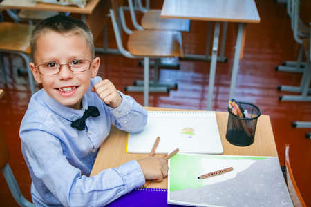 Happy child at school desk at school after schoolの写真素材