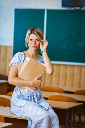 Happy teacher with books in classroom room back to school