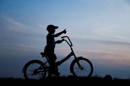 a silhouette of a boy on a bicycle in natureの写真素材