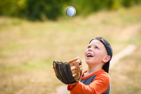 Happy child with baseball ball on nature concept in parkの写真素材