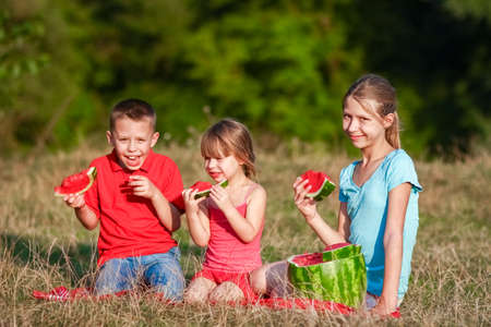 Happy kids eating watermelon concept on nature in parkの写真素材