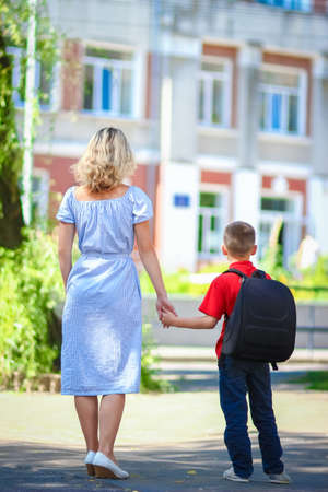 Happy mom leads the child to school on the way back to schoolの写真素材