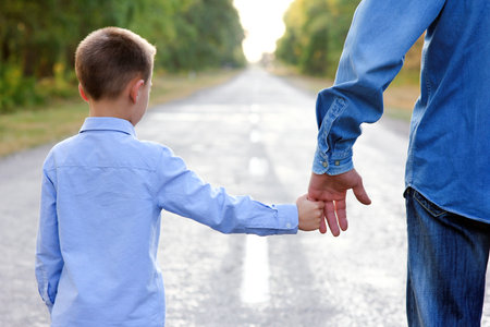 Happy parent with a child in the park hands on nature travel go along the road concept familyの写真素材