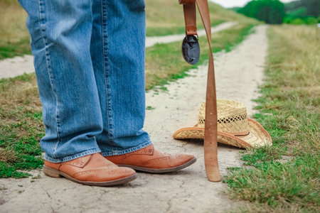Cowboy legs in shoes in the park on nature background. The man at the ranch.