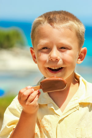 Happy child boy with ice cream by the sea in nature in the park journeyの写真素材