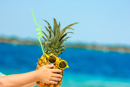 Pineapple in the hands of a man by the sea in nature on a journey backgroundの写真素材