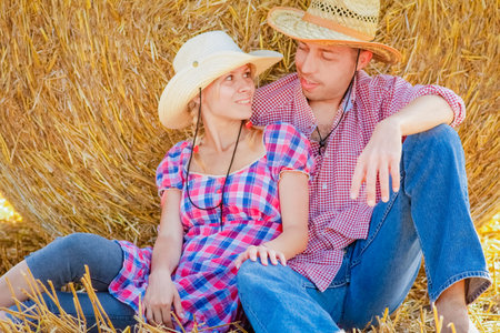 happy couple on the field with bales harvest in autumn