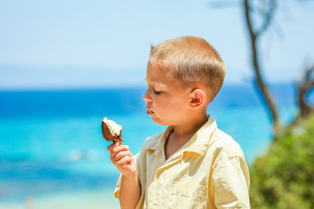 Happy child boy with ice cream by the sea in nature in the park journeyの写真素材