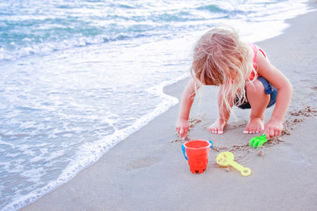 Happy child draw pictures in the sand of the sea in the summer on the natureの写真素材