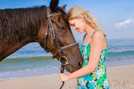 Happy pregnant woman with a horse on the beach in the summer on the natureの写真素材