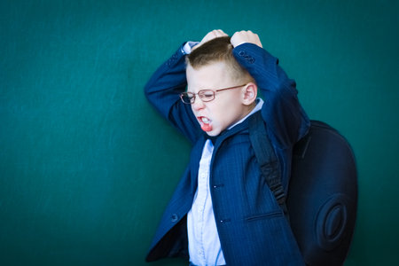 Happy child child standing at the blackboard with a school backpack wearing glassesの写真素材
