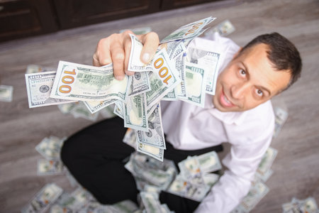 Happy guy with money in his hands for the development of shopping business and a great tripの写真素材