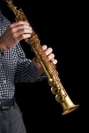 soprano saxophone in hands on a black backgroundの写真素材