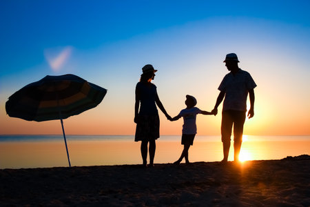Happy family by the sea at sunset in travel silhouette in natureの写真素材