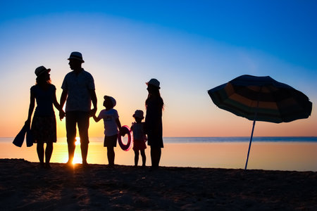Happy family by the sea at sunset in travel silhouette in natureの写真素材
