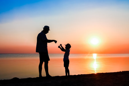 Happy parent with child by the sea play on nature silhouette travelの写真素材