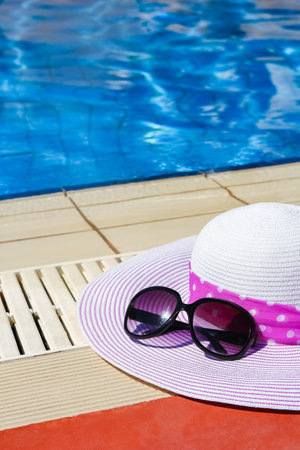 beautiful hat near the pool with cream and glasses backgroundの写真素材