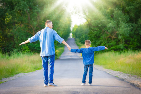 Happy child on the shoulders of a parent in nature on the way to travelの写真素材