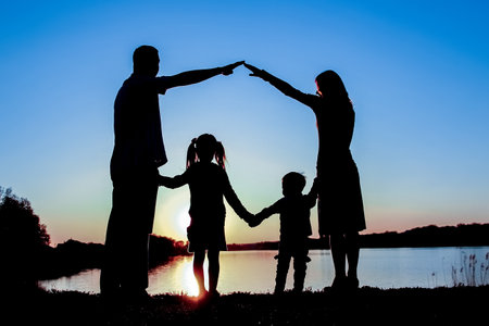 silhouette family, including his father, mother and two children in the hands ofの写真素材