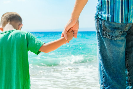 Hands of a happy parent and child on the seashore on a journey trip in natureの写真素材