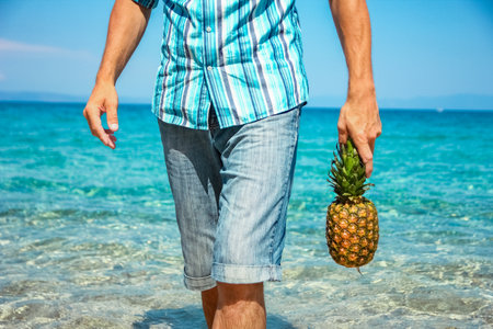 happy man with a pineapple in his hands near the sea in nature weekend travelの写真素材