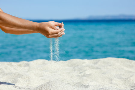 hands pouring sand near the seashore on weekend nature travelの写真素材
