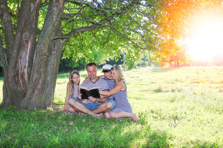happy family reading bible in natureの写真素材