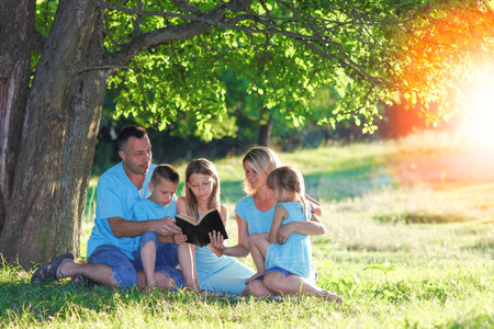 happy family reading bible in natureの写真素材