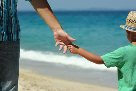 Hands of a happy parent and child on the seashore on a journey trip in natureの写真素材