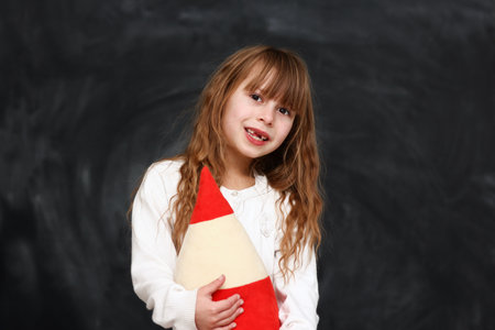happy little girl student emotions with a big pencil on black background