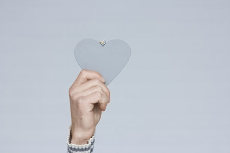 Heart in human hands on white brick backgroundの写真素材