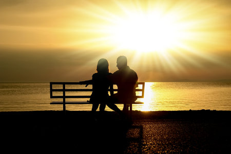 happy couple on a bench by the sea on nature in travel silhouetteの写真素材