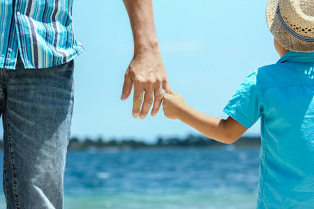 happy dad holds the hand of a child by the greek sea in natureの写真素材