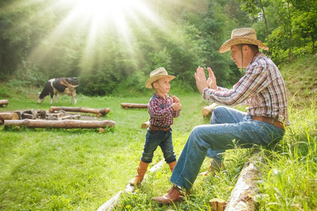 happy child with cowboy parent in nature in the fieldの写真素材