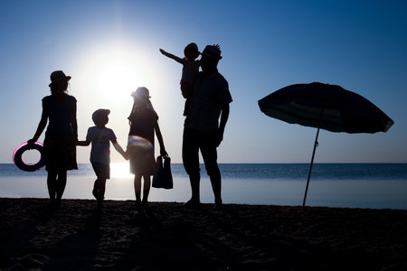 Happy family by the sea at sunset in travel silhouette in natureの写真素材