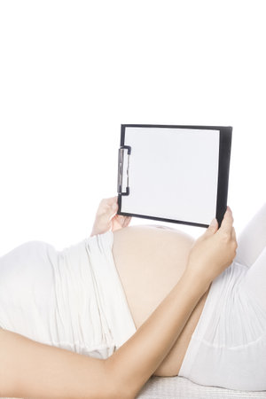 Happy pregnant girl lies on white backgroundの写真素材