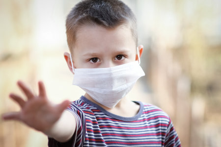 Coronavirus and air pollution PM2.5 concept. European little boy wearing mask for protect pm2.5 and shows stop hand gesture to stop the outbreak of the corona virus. Mass symptoms of coronavirus and epidemic virus.の写真素材