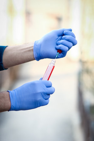 In the hands of a test tube with blood for analysis of the virus. Covid-19 is a danger to the infectious air population.の写真素材