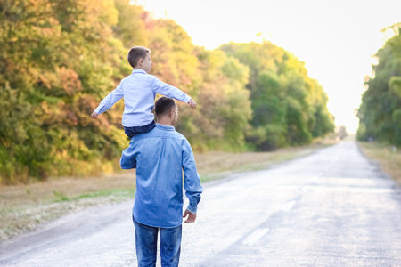 Happy parent with a child in the park hands on nature travel go along the roadの写真素材