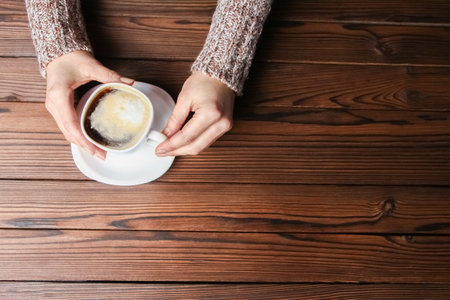female hands and coffee on wooden backgroundの写真素材