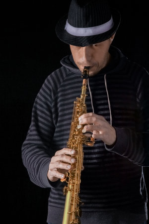 soprano saxophone in the hands of a guy on a black backgroundの写真素材
