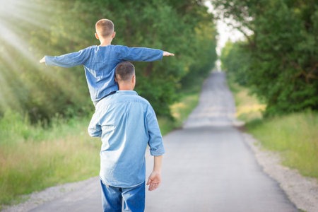 Happy child on the shoulders of a parent in nature on the way to travelの写真素材