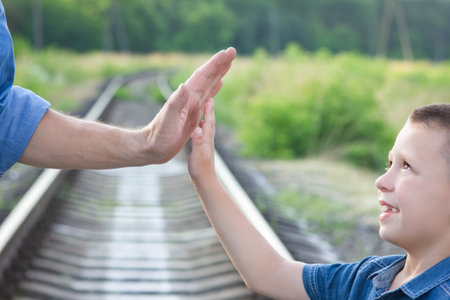 Hands of a happy parent and child in nature in the travel parkの写真素材